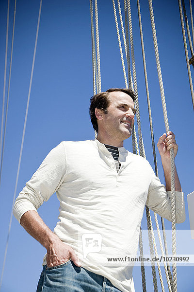 Mature man on a sailing ship holding rope