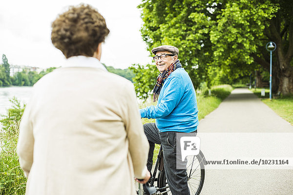 Glücklicher älterer Mann mit Fahrrad von Angesicht zu Angesicht mit seiner Frau