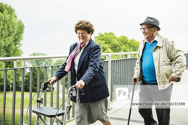 Senior couple with walking stick and wheeled walker