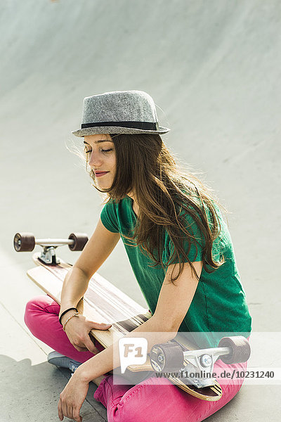 Lächelnder junger Skateboarder mit geschlossenen Augen und Hut