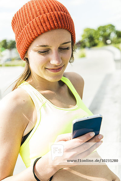 Portrait of smiling young woman with smartphone wearing woolly hat