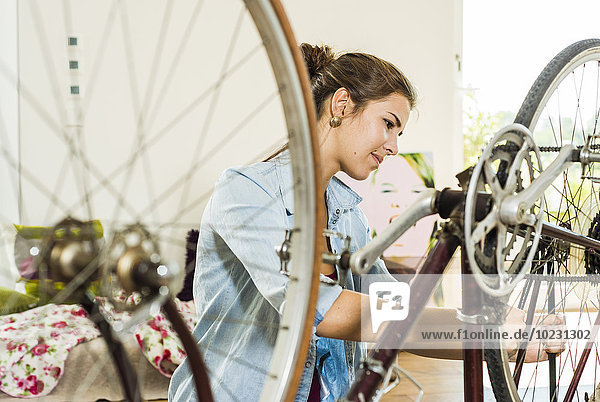 Junge Frau zu Hause repariert ihr Fahrrad