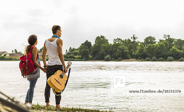 Junges Paar am Flussufer mit Gitarre
