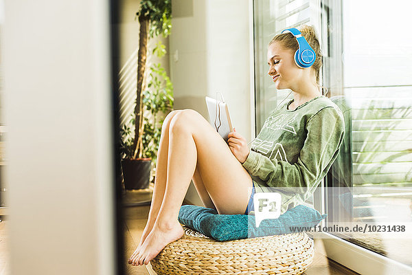 Teenager-Mädchen liegt zu Hause und hört Musik vom digitalen Tablett.
