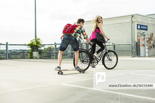 Glückliches junges Paar mit Fahrrad und Skateboard