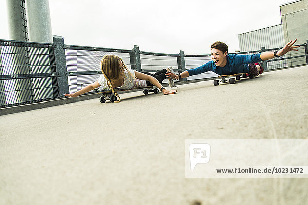 Begeistertes junges Paar beim Abfahren mit Skateboards