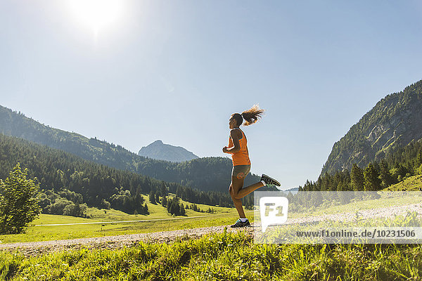 Österreich  Tirol  Tannheimer Tal  junge Frau beim Joggen in alpiner Landschaft
