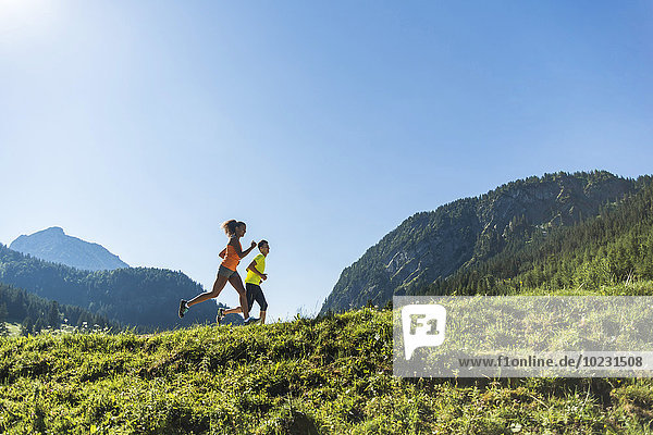 Austria  Tyrol  Tannheim Valley  young couple jogging in alpine landscape