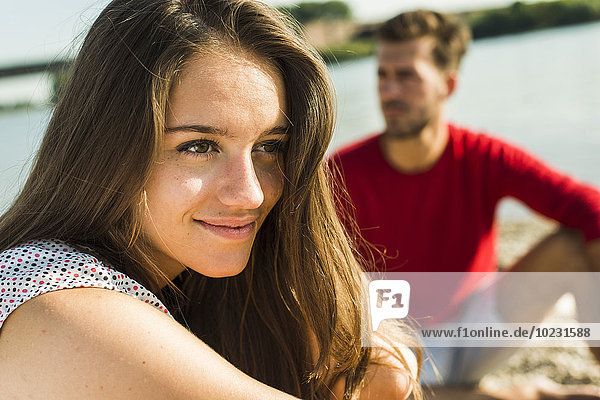 Lächelnde junge Frau und Mann am Flussufer