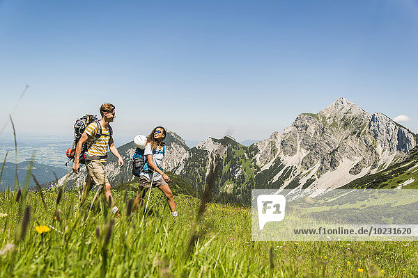 Austria  Tyrol  Tannheimer Tal  young couple hiking on alpine meadow