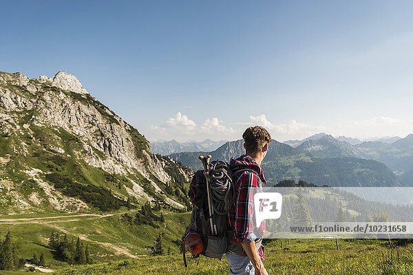 Austria  Tyrol  Tannheimer Tal  young man hiking on alpine meadow
