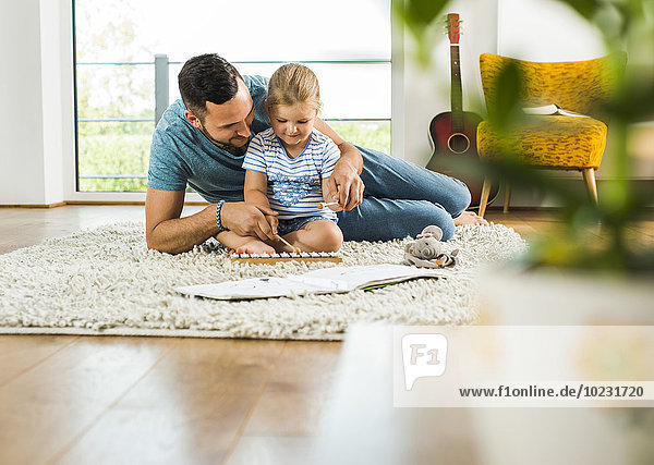 Father with daughter on rug playing glockenspiel