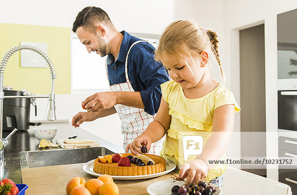 Father and daughter in kitchen preparing fruit cake