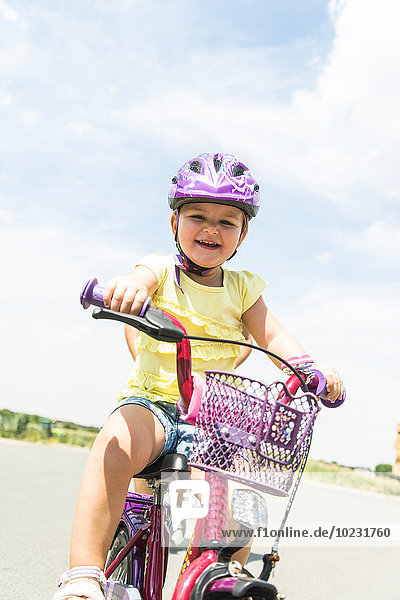Glückliches kleines Mädchen auf dem Fahrrad