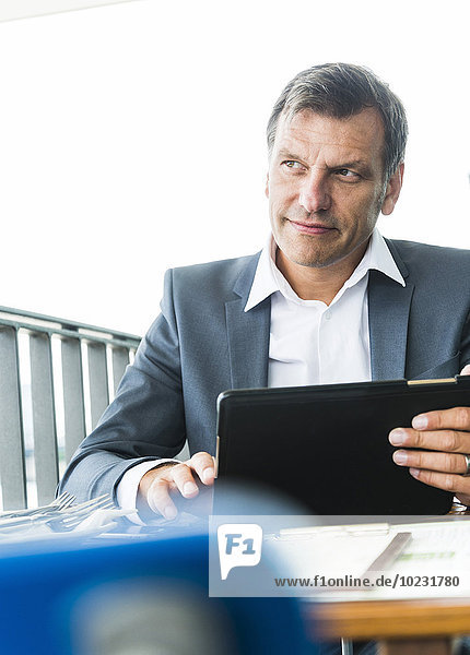 Businessman sitting outdoors  using digital tablet