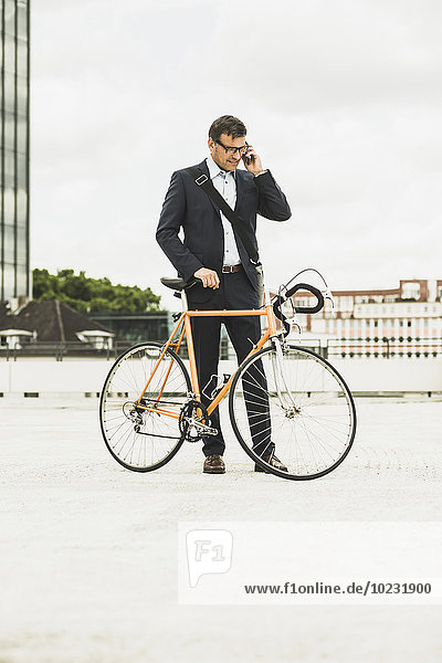 Geschäftsmann am Telefon  Fahrrad haltend
