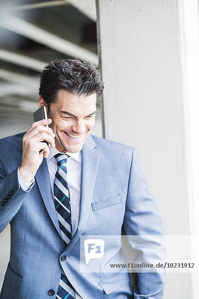 Portrait of smiling businessman telephoning with smartphone