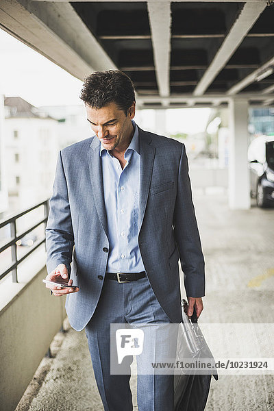 Geschäftsmann mit Aktentasche beim Blick auf sein Smartphone