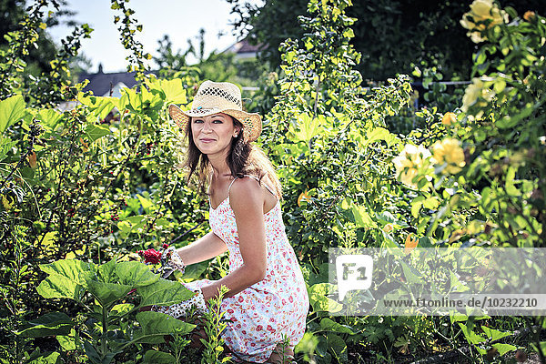 Porträt einer lächelnden Frau bei der Arbeit im Garten