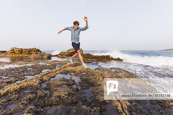 Griechenland  Rhodos  junger Mann springt auf Felsen am Meer