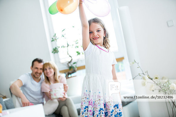 Mädchen spielt mit Luftballons  Eltern schauen zu