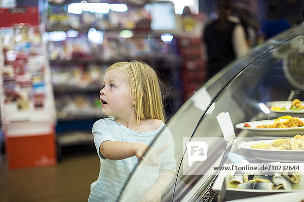 Little girl pointing at food at display