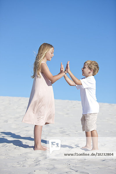 Geschwister spielen am Sandstrand