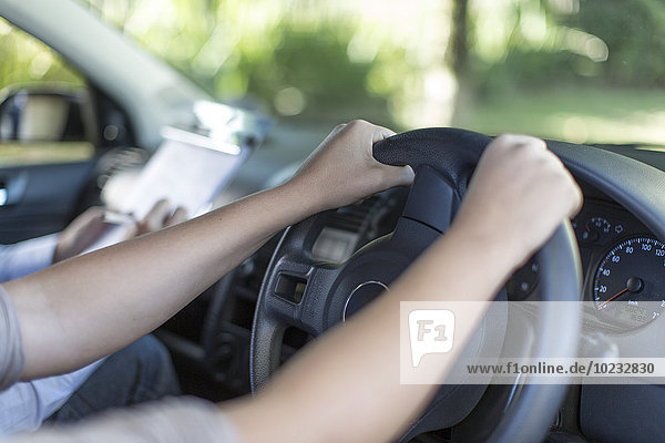 Hands of teenage girl at car steering wheel