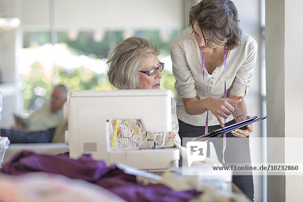 Senior woman and adult daughter working on sewing machine