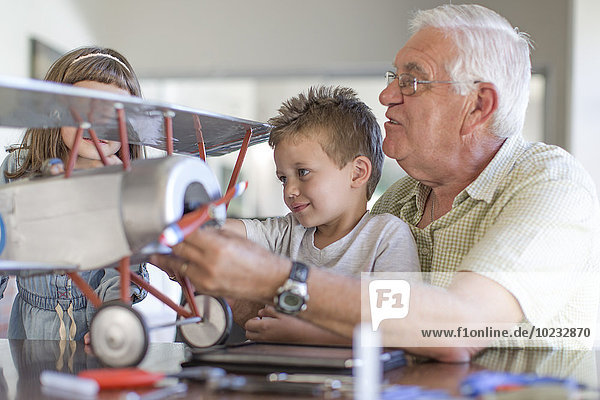 Großvater und Enkelkinder beim Aufbau eines Modellflugzeugs