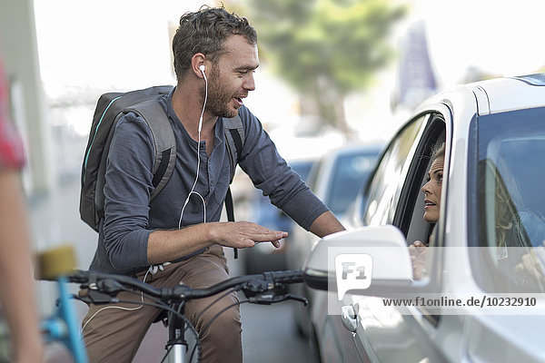 Mann auf dem Fahrrad im Gespräch mit Frau im Auto