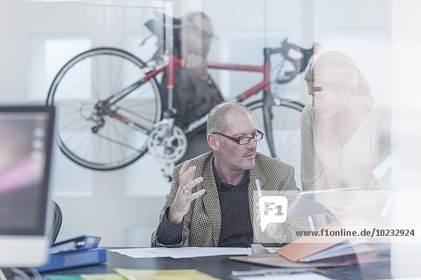 Geschäftsleute diskutieren im Büro  über das Tragen von Fahrrädern im Hintergrund