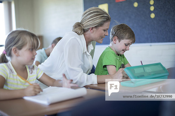 Lehrer hilft Schuljunge im Klassenzimmer
