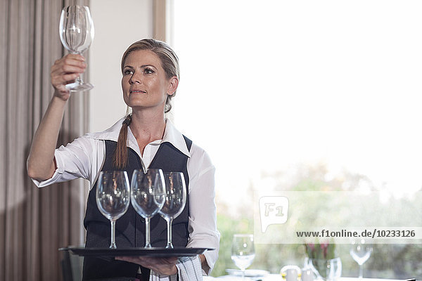 Kellnerin mit leeren Weingläsern auf dem Tablett