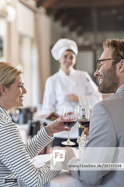 Mid adult couple in restaurant toasting with redwine