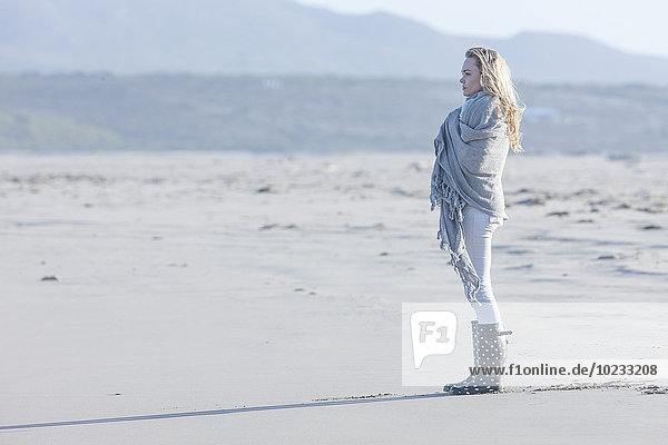 Südafrika  Kapstadt  junge Frau  die am Strand steht und in die Ferne schaut.