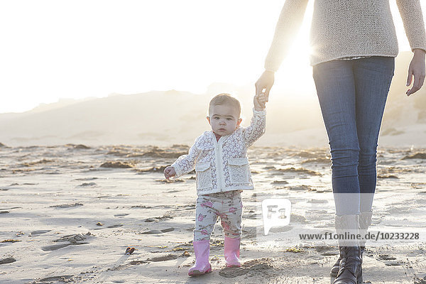 Südafrika  Kapstadt  kleines Mädchen  das die Hand der Mutter am Strand hält
