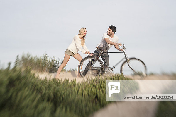Young couple with bicycle on a beach dune