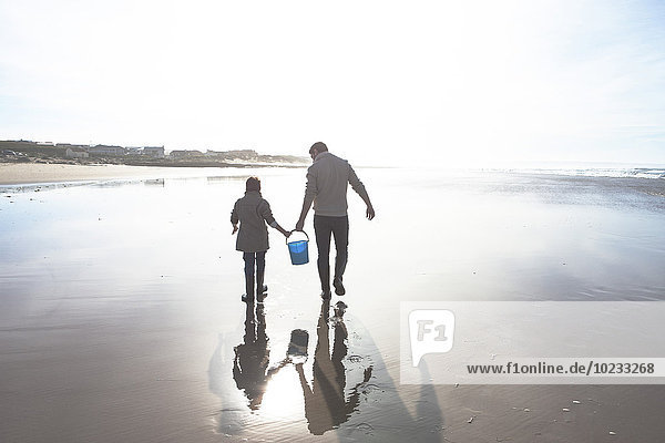 Südafrika,  Witsand,  Vater und Sohn beim Spaziergang am Strand im Gegenlicht