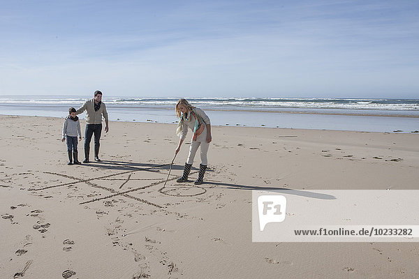Südafrika  Witsand  Familie spielt tic tac toe am Strand