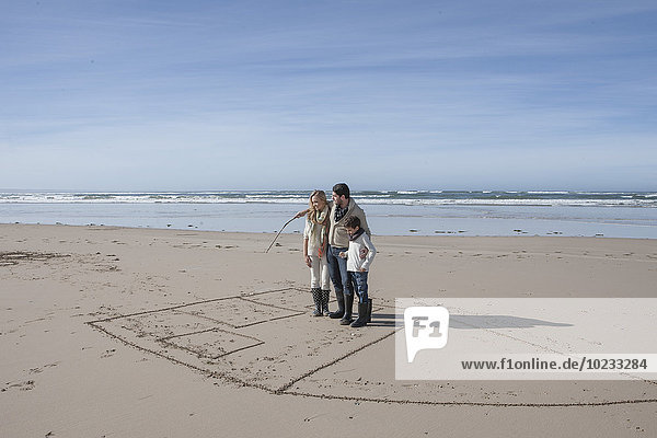 Südafrika,  Witsand,  Familie spielt tic tac toe am Strand