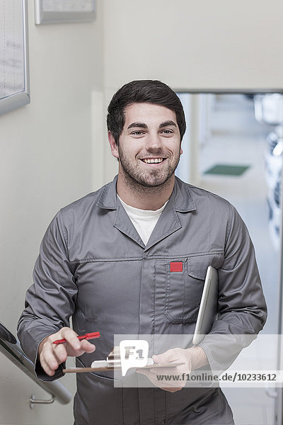 Smiling car mechanic holding clipboard