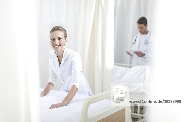 Smiling nurse making hospital bed