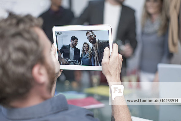 Mann fotografiert Kollegen auf einem digitalen Tablett