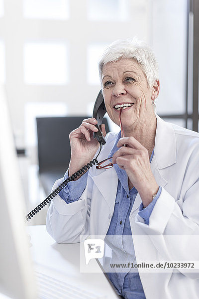 Smiling senior woman in lab coat on the phone