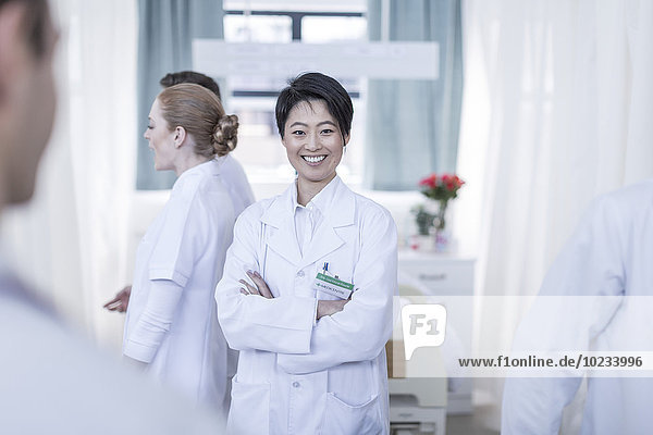 Porträt eines lächelnden Arztes umgeben von Krankenhauspersonal