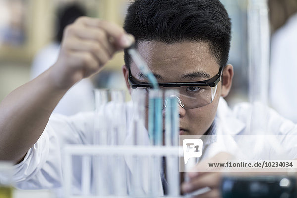 Student der Chemieklasse Pipettieren von Flüssigkeit in ein Reagenzglas