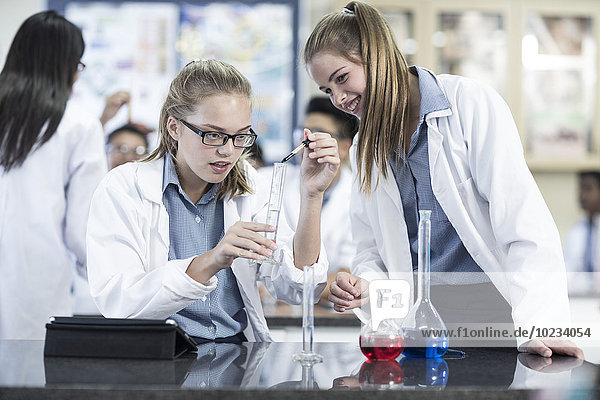 Two schoolgirls in chemistry class working with liquids