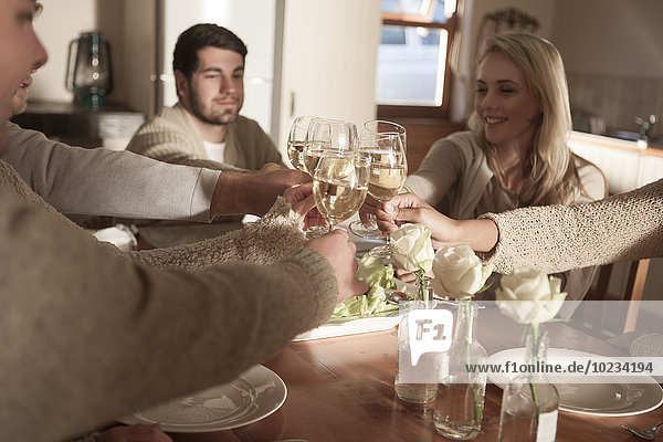 Friends clinking wine glasses at dinner table