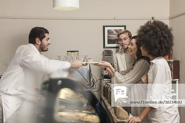 Customers queuing at cake counter in coffee shop